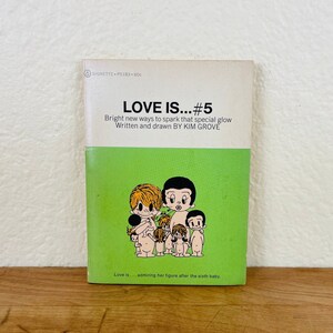 May include: A vintage paperback book titled "LOVE IS...#5". The cover features a green and white design with the title in bold letters. The book's illustration shows a group of cartoon figures. The text reads "Bright new ways to spark that special glow".