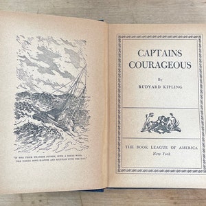 May include: Open book titled "Captains Courageous" by Rudyard Kipling. The cover features a black and white illustration of a ship at sea. Published by The Book League of America, New York.