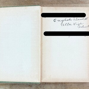 K&ouml;nnte beinhalten: Ein aufgeschlagenes Hardcover-Buch mit gr&uuml;nem Buchr&uuml;cken und cremefarbenen Vorsatzbl&auml;ttern. Auf der rechten Seite befindet sich handschriftlicher Kursivtext mit der Aufschrift English Class II Alba High School, der von zwei schwarzen Balken verdeckt wird.