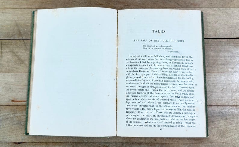 K&ouml;nnte beinhalten: Ein aufgeschlagenes altes Buch mit cremefarbenen Seiten und dunkelgr&uuml;nem Einband. Die rechte Seite zeigt den Titel TALES, den Untertitel THE FALL OF THE HOUSE OF USHER und einen gedruckten englischen Textabschnitt, der mit During the whole of a dull beginnt.