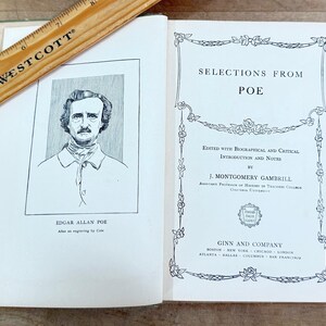 K&ouml;nnte beinhalten: Ein aufgeschlagenes Buch mit dem Titel Selections from Poe, herausgegeben von J. Montgomery Gambrill, mit einem Portr&auml;t von Edgar Allan Poe auf der linken Seite. Ein h&ouml;lzernes Westcott-Lineal liegt diagonal dar&uuml;ber und zeigt Ma&szlig;e in Zentimetern.