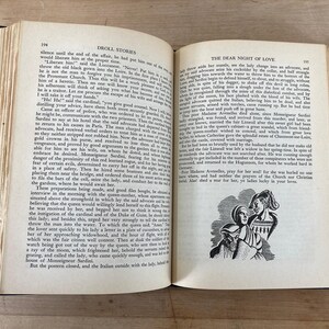 May include: An open book with aged, yellowed pages. The text is in English, with the title "Droll Stories" visible. A black and white illustration of three figures is on the right page.
