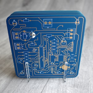 May include: Blue and gold circuit board design coasters. The coasters are made of a durable material and feature a unique design that is perfect for any home.