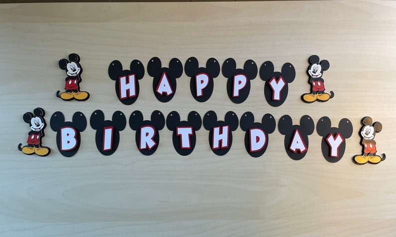May include: Black and white Mickey Mouse themed banner with the words "Happy Birthday" in white letters on black Mickey Mouse ears.