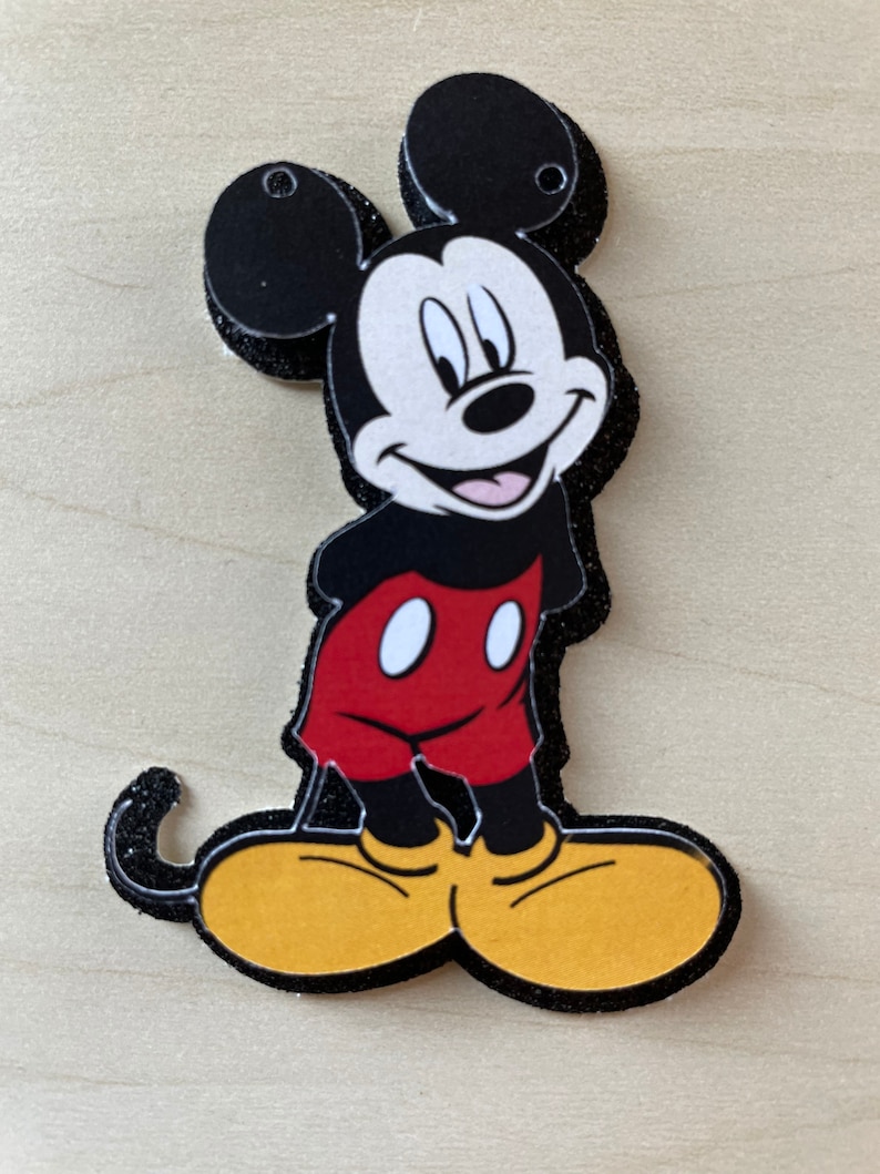 May include: A black and red cartoon character with large ears and yellow shoes. The character is smiling and has a black outline.