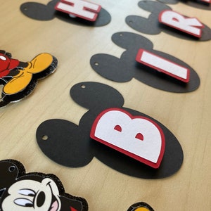 May include: Black and red Mickey Mouse themed banner with the words "Happy Birthday" in white letters.