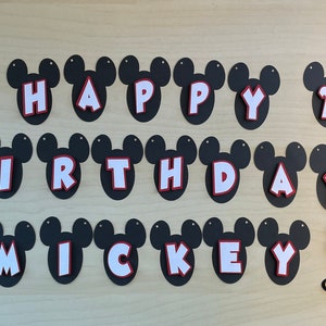 May include: A black and white Mickey Mouse themed birthday banner with the words "Happy 2nd Birthday Mickey" in white letters with red outlines. The banner is decorated with Mickey Mouse heads and figures.