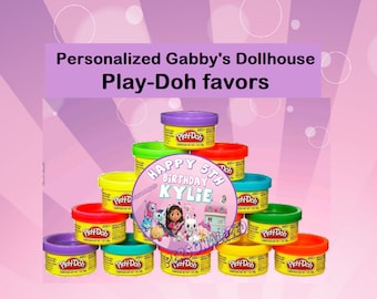Puede incluir: Una pila de recipientes de Play-Doh con una etiqueta personalizada que dice "Feliz 5º cumpleaños Kylie". La etiqueta presenta una imagen de dibujos animados de Gabby de Gabby's Dollhouse y sus amigos.