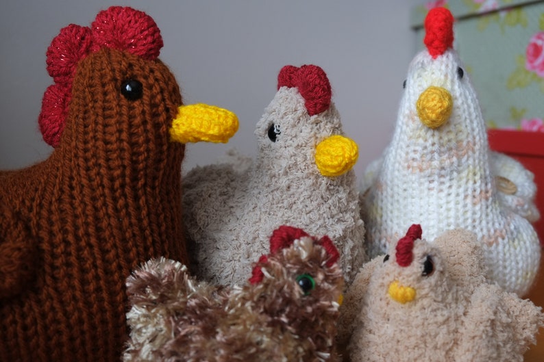 May include: Five knitted chicken toys. One is brown with a red comb, one is white with a red comb, one is beige with a red comb, one is beige with a red comb and a yellow beak, and one is brown with a red comb and a yellow beak.