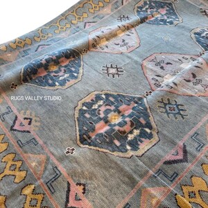 Puede incluir: Una alfombra vintage con fondo azul y patrones intrincados en tonos de rosa, amarillo y azul. La alfombra tiene un dise&ntilde;o geom&eacute;trico con un medall&oacute;n central y un borde.