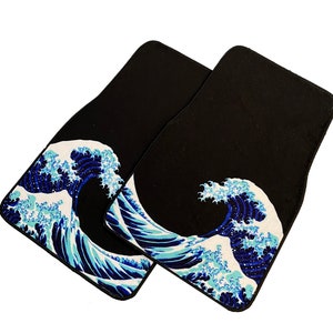 K&ouml;nnte beinhalten: Zwei schwarze Fu&szlig;matten mit einem blauen und wei&szlig;en Wellendesign. Das Wellendesign ist ein japanischer Kunstdruck.