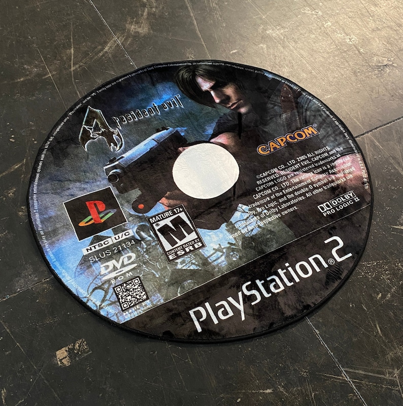 May include: Circular rug featuring the Resident Evil 4 video game disc design. The rug displays the game's title, character art, and PlayStation 2 logo. Includes the ESRB rating and other game details.