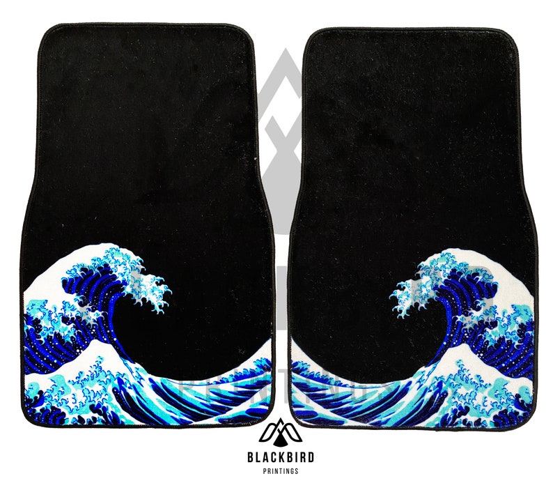 K&ouml;nnte beinhalten: Zwei schwarze Autofu&szlig;matten mit einem blauen und wei&szlig;en Wellendesign. Das Wellendesign erinnert an die Gro&szlig;e Welle vor Kanagawa, ein ber&uuml;hmter japanischer Holzschnitt.
