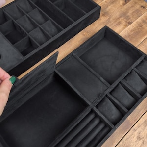 May include: Black velvet jewelry organizer with multiple compartments for rings, watches, and other accessories. The organizer has a rectangular shape and is designed to store and protect jewelry. The image shows the organizer open and closed.