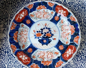 An antique Imari decorative hand painted plate with a frilled edge in rich blues and reds, of flowers.