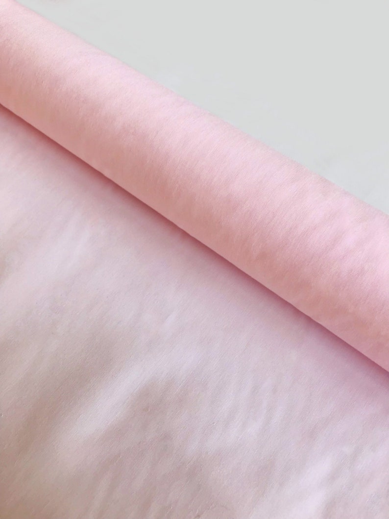 May include: A roll of pale pink tissue paper. The paper is soft and delicate, perfect for wrapping gifts or creating crafts.