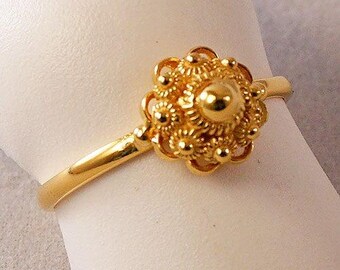 May include: A gold ring with a detailed floral design. The ring is made of a single band with a large, ornate flower-shaped centerpiece.