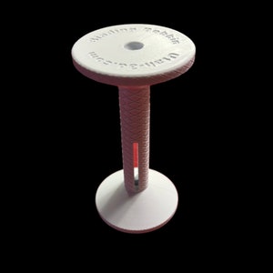 May include: White plastic film reel spool with a textured center and the text "Waren-S.G.m.b.H. Berlin" on the top.