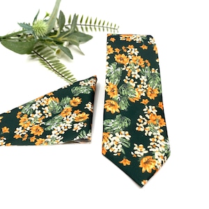 Puede incluir: Una corbata y un pañuelo de bolsillo verdes con un estampado floral con flores naranjas y blancas.