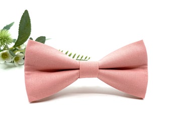 May include: A light pink bow tie made of fabric.