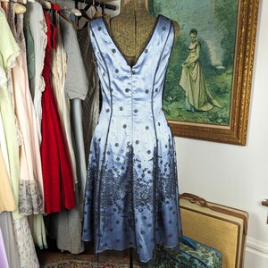 May include: A light blue sleeveless dress with black lace detailing. The dress has a fitted bodice and a flowing skirt.