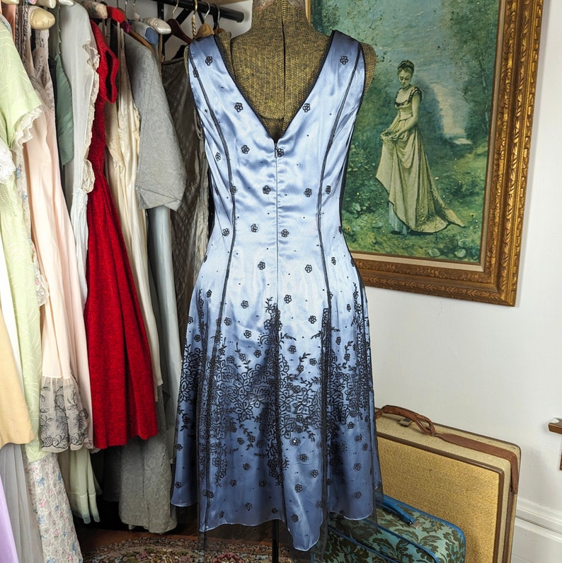 May include: A light blue sleeveless dress with black lace detailing. The dress has a fitted bodice and a flowing skirt.