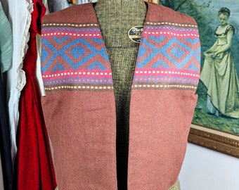 May include: A brown waistcoat with a geometric pattern in shades of blue, pink, and white. The waistcoat is made of a soft, textured fabric and has a V-neck.