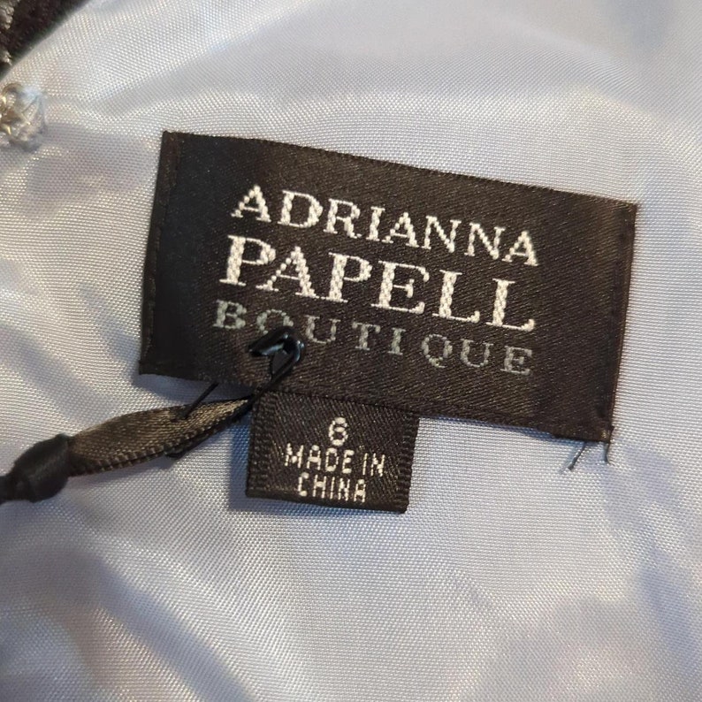 May include: A black and white label with the text "Adrianna Papell Boutique" and a smaller label that says "Made in China".