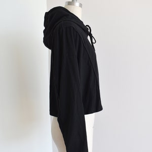 Black hoodie in lightweight t-shirt cotton, tonal piping along sleeves and chest, drawstring with silver endings