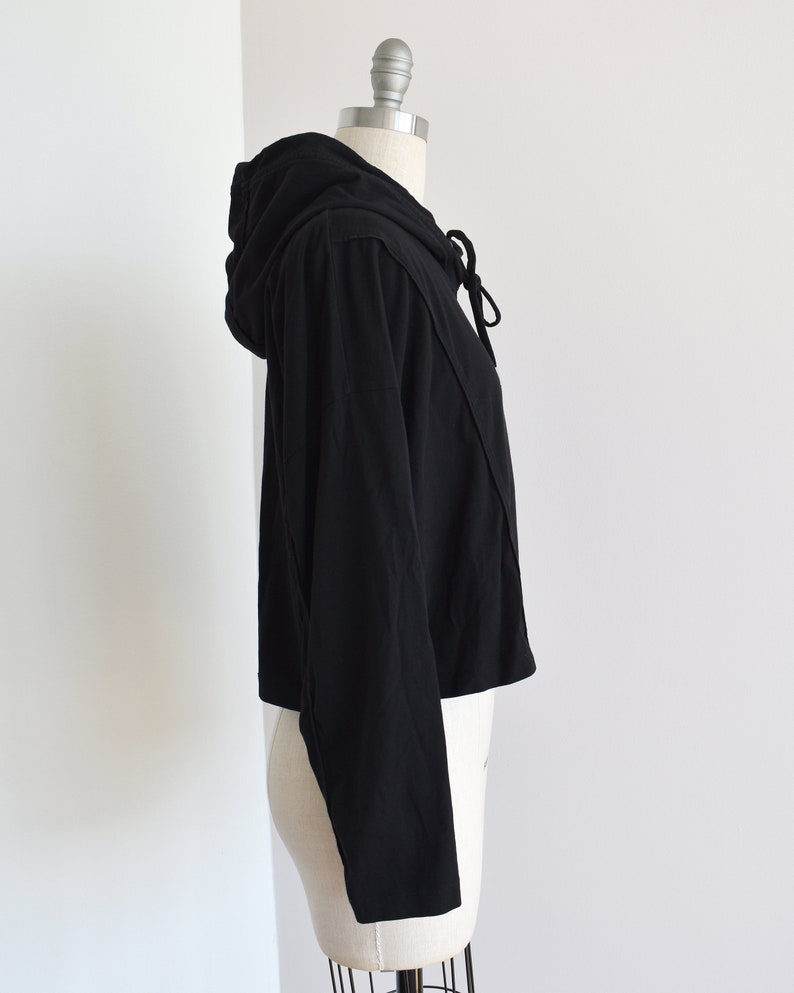 Black hoodie in lightweight t-shirt cotton, tonal piping along sleeves and chest, drawstring with silver endings