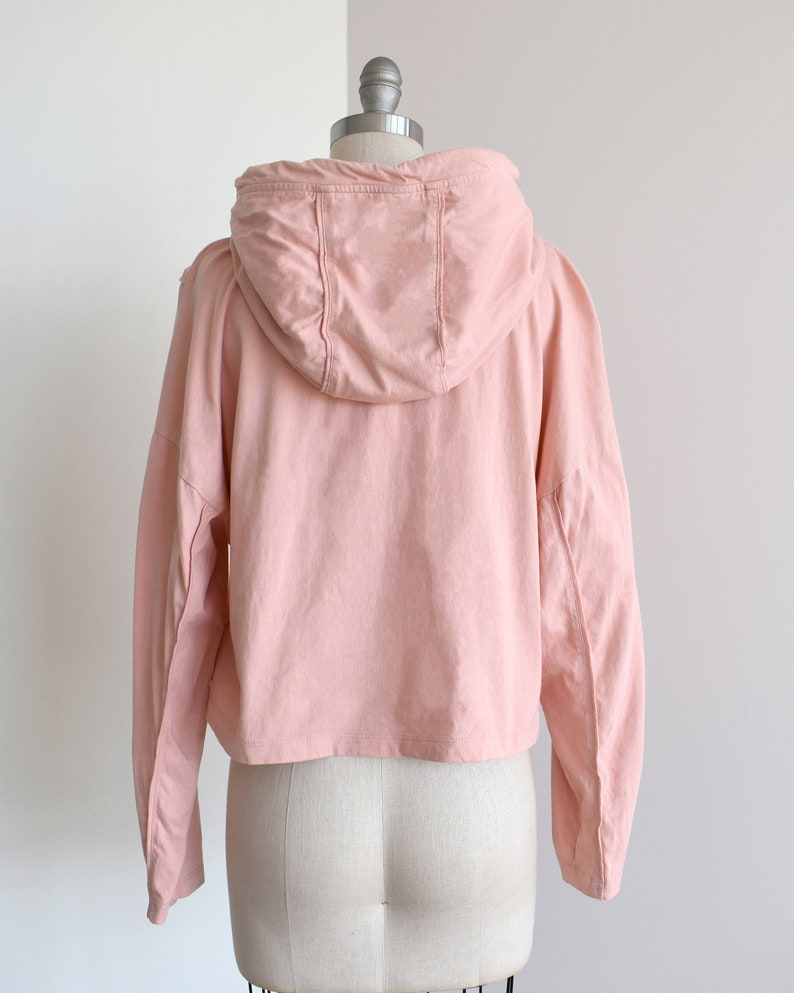 Light pink hoodie in lightweight t-shirt cotton, tonal piping along sleeves and chest, drawstring with silver endings