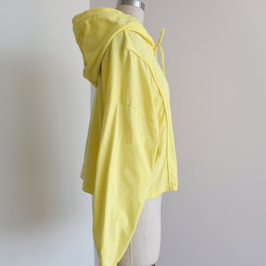 Yellow hoodie in lightweight t-shirt cotton, tonal piping along sleeves and chest, drawstring with silver endings