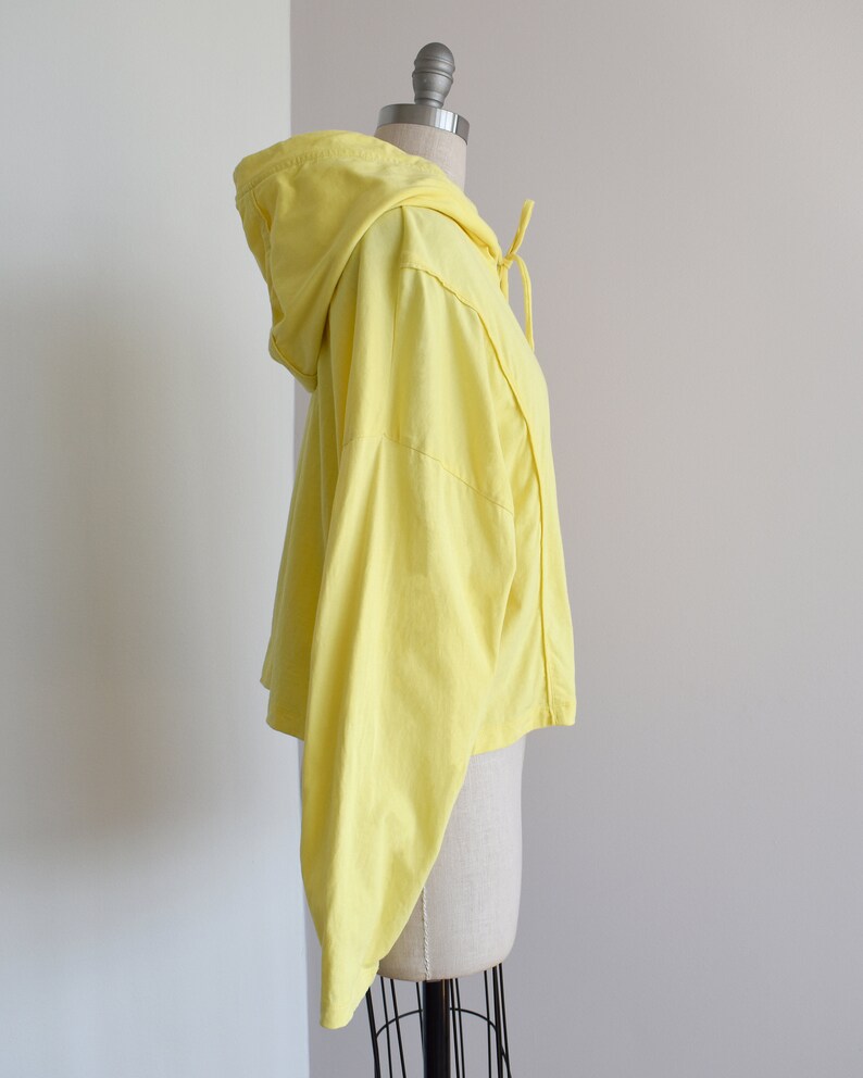 Yellow hoodie in lightweight t-shirt cotton, tonal piping along sleeves and chest, drawstring with silver endings