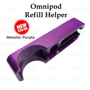 Può includere: Uno strumento Omnipod Refill Helper viola metallizzato con una finitura testurizzata stampata in 3D. Il dispositivo presenta un corpo curvo e allungato con un ritaglio centrale e un grafico a stella rossa con il testo NEW COLOR.