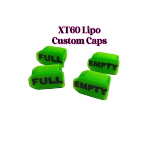 Peut inclure: Quatre bouchons personnalisés XT60 Lipo verts vifs sont présentés sur fond blanc. Deux bouchons portent l'inscription "FULL" en noir, et les deux autres "EMPTY". Les bouchons sont petits, rectangulaires et semblent être en matière souple.