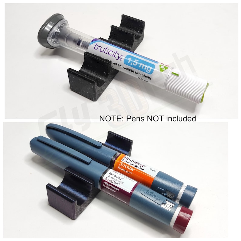 May include: A black 3D printed pen holder with two slots for insulin pens. The holder is shown with two insulin pens, one blue and one orange. The text on the pens reads "Humalog Junior 100 unidades/ml KwikPen" and "Humalog KwikPen".