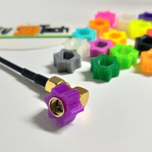May include: A selection of brightly coloured, star-shaped connectors in shades like purple, green, and orange. A black cable with a purple connector is visible. These connectors are likely for electronic devices.