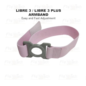 Op de afbeelding: Een lichtroze elastische armband met een grijze ronde kunststof houder. De tekst LIBRE 3 / LIBRE 3 PLUS ARMBAND en Easy and Fast Adjustment staat erboven. De band is voorzien van een klittenbandsluiting voor eenvoudige verstelling.