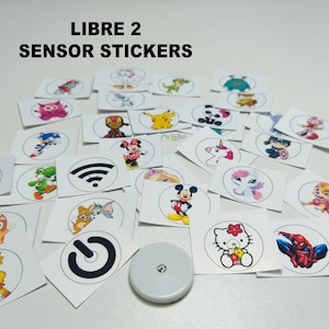 Puede incluir: Una colección de pegatinas redondas y coloridas con varios personajes de dibujos animados, incluyendo Mickey Mouse, Hello Kitty y Spiderman. Las pegatinas están diseñadas para ser usadas con el sensor Libre 2.