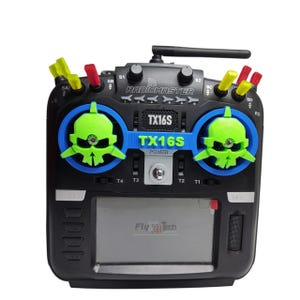Puede incluir: Transmisor RadioMaster TX16S negro con detalles de calaveras verdes y azules. El controlador tiene múltiples interruptores, perillas y una pantalla que muestra "Fly 3D Tech". TX16S y Power están impresos en la parte delantera.