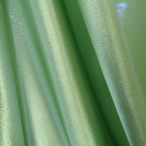 May include: A close-up of a green fabric with a subtle shimmer. The fabric is folded and draped, showing its texture and drape.