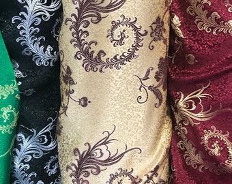 May include: Three rolls of fabric with different patterns. The fabric on the left is black with a silver floral design. The middle fabric is beige with a brown floral design. The fabric on the right is red with a gold floral design.