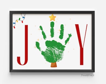 May include: Framed print with the word "JOY" in red letters. The "O" is a green handprint shaped like a Christmas tree, topped with a gold star. A string of colorful lights and gold sparkles add festive cheer.