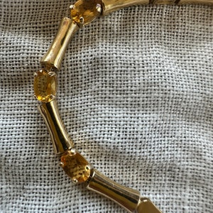 May include: A gold bracelet with a bamboo-style design and oval-shaped amber gemstones.