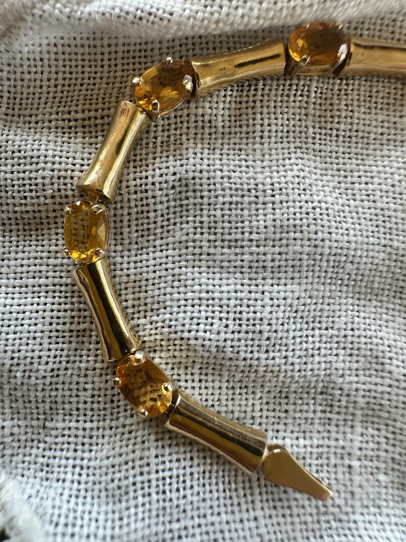 May include: A gold bracelet with a bamboo-style design and oval-shaped amber gemstones.