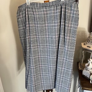 May include: A black and white plaid skirt with a pink stripe. The skirt has a waistband and a button closure.