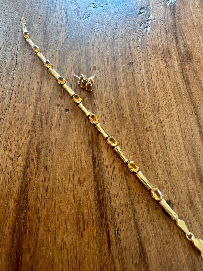 May include: A gold bracelet with a bamboo-style design and oval-shaped orange gemstones. A pair of matching earrings with orange gemstones are also included.