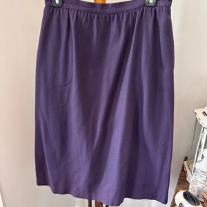 May include: A purple knee-length skirt with a simple design. The skirt is made of a smooth, woven fabric.