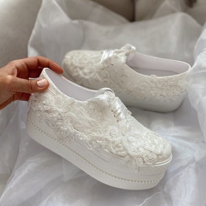 May include: White lace platform trainers with a pearl trim. The trainers have a white satin ribbon tied around the laces.