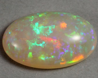 May include: A light brown oval opal gemstone with green, purple, and orange flashes of color.